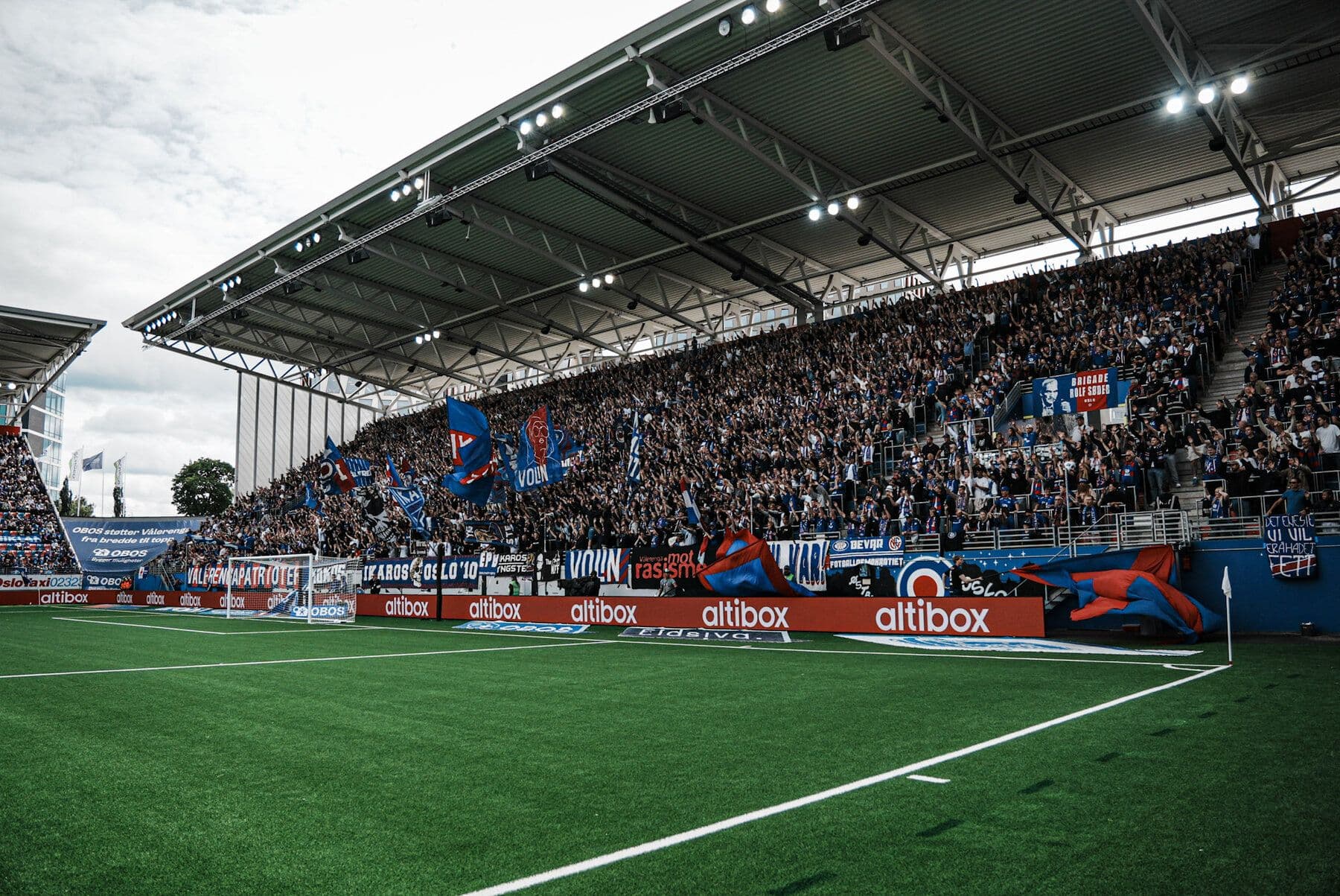 Full tribune med Vålerenga-supportere og LED-boards langs banen på Intility Arena